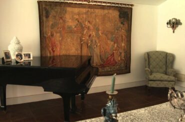 Tilting up shot in a Italian room with a dining table and a baby grand piano.