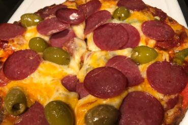 Pizza cooking extra cheese and salami and olives