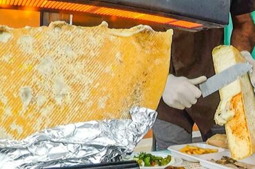 Cascades of 'Raclette' Melted Cheese on Roasted Meat. Italy Street Food Festival