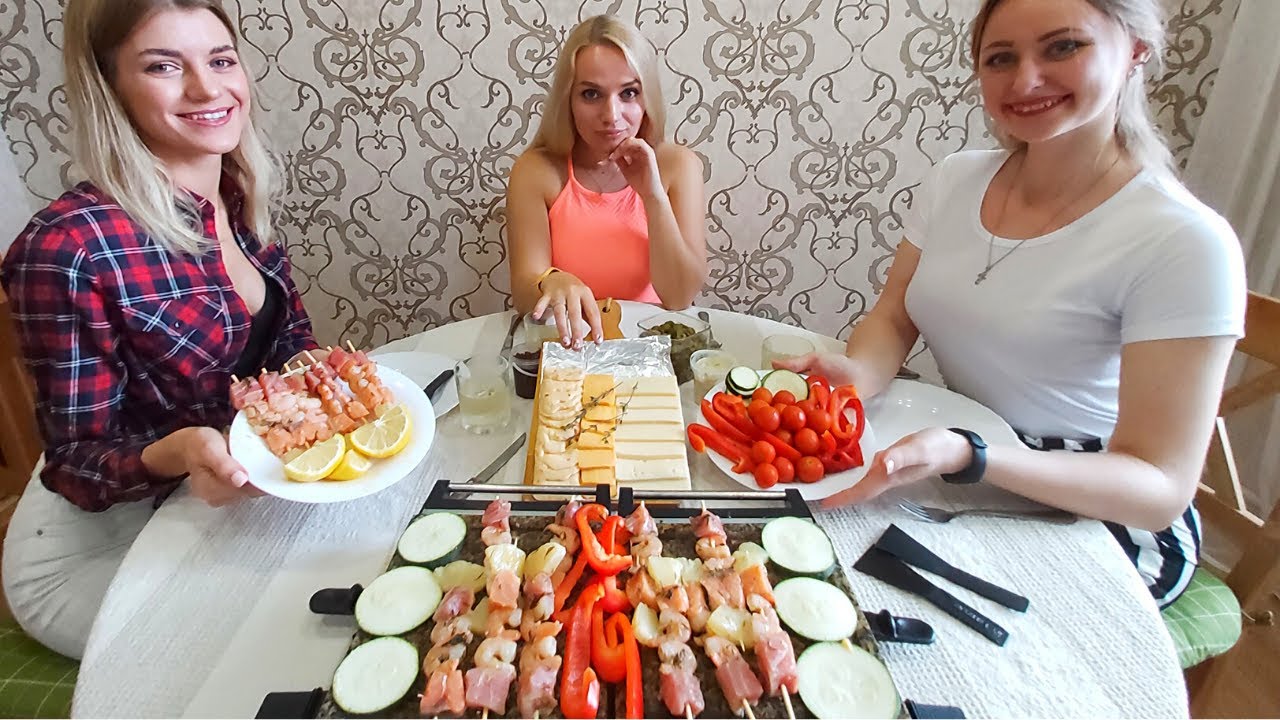 Russian Girls Eating Swiss Raclette. Melted Cheese over Grilled Meat Russian Girls Eating Swiss Raclette. Melted Cheese over Grilled Meat