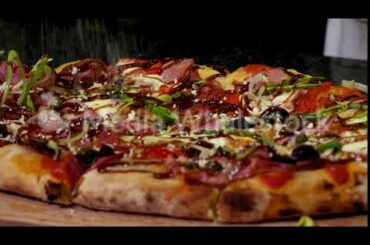 Close up for hands sprinkling delicious pizza with parmesan cheese, italian food concept. Frame