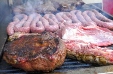 Italy Street Food Festival. Huge Asado, Blocks of Meat on Grill, Big Sausages, Ham and more Food