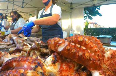 Italy Street Food. Women Master Grill of Huge Octopuses Fast. Milan Food Festival