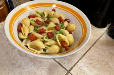 Pasta Shells with Onion and Peas Garnished with Guanciale in Parmesan Cheese sauce.
