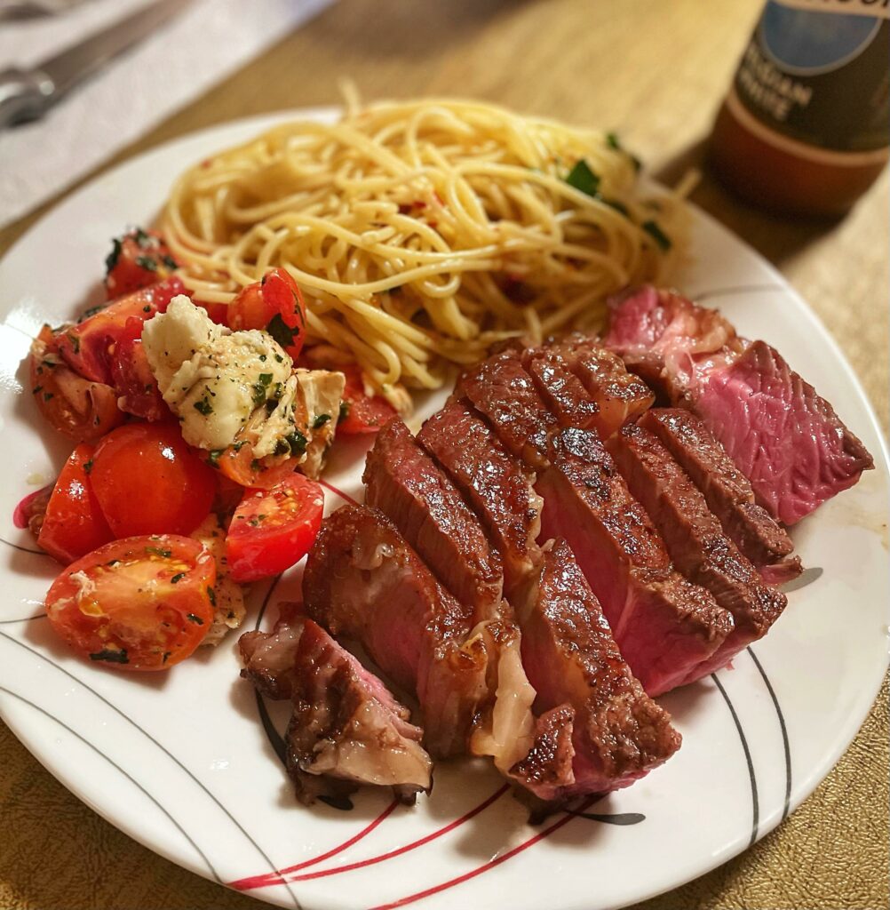 A beautiful ribeye with Spaghetti Aglio e Oilio & Caprese 🤤