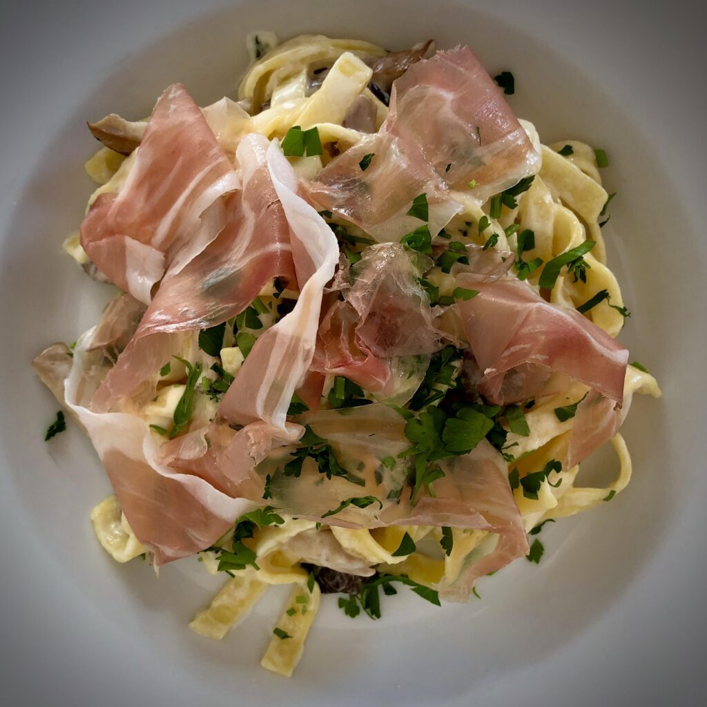 Homemade fettuccine with speck and mushrooms