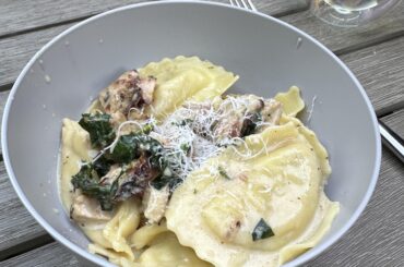 Sausage ravioli in a white wine cream sauce with grilled chicken and spinach
