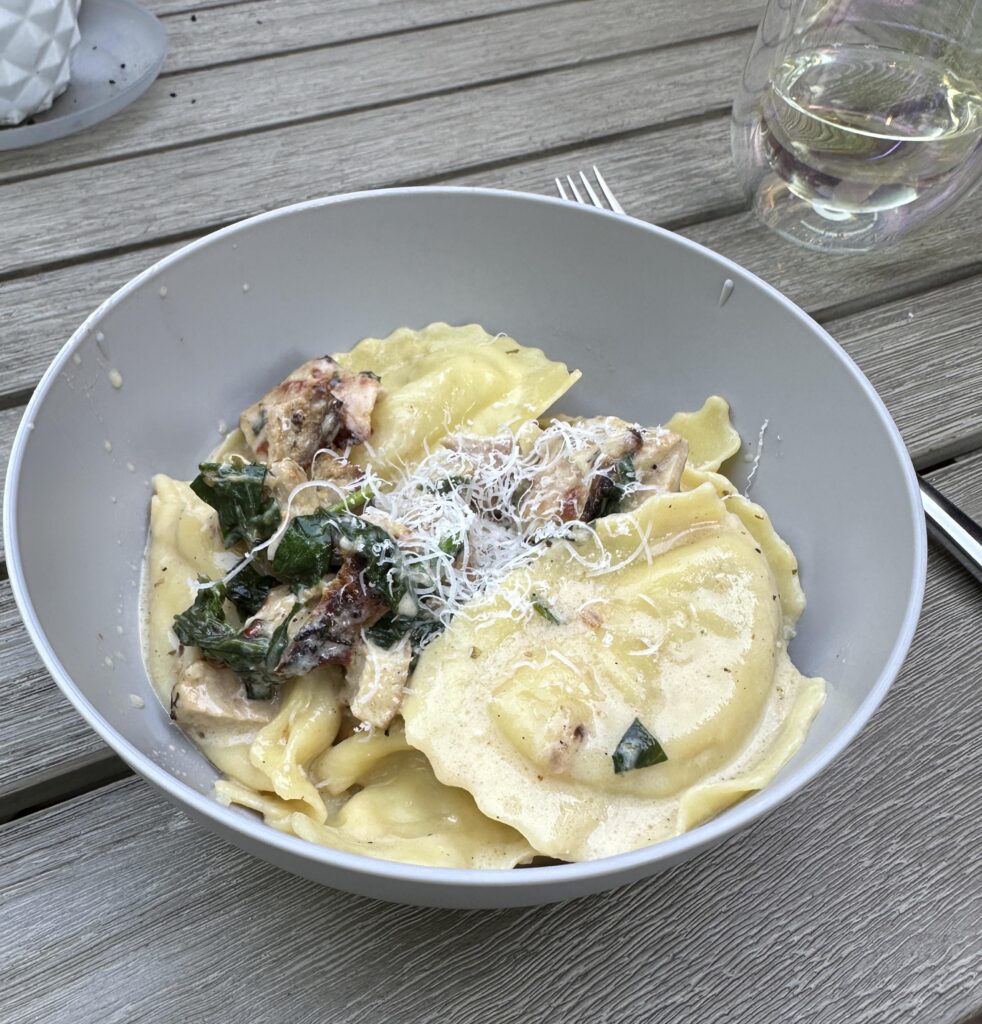 Sausage ravioli in a white wine cream sauce with grilled chicken and spinach