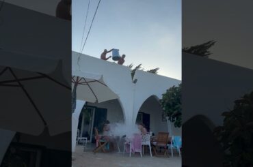 People drenched with water while dining outside in San Foca, Italy