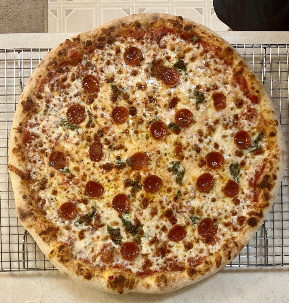 Homemade pizza. Pepperoni and basil under cheese