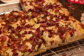 Detroit style pizza with white sauce, red onion, shaved brussel sprouts, bacon, and hot honey