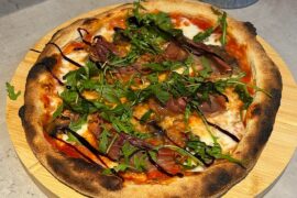 Prosciutto, garlic mushroom pizza topped with rocket and a balsamic glaze, and a garlic bread