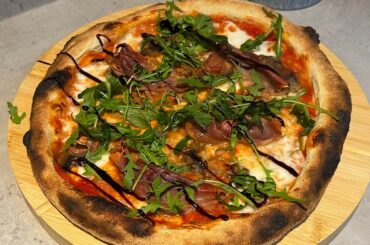 Prosciutto, garlic mushroom pizza topped with rocket and a balsamic glaze, and a garlic bread