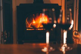 Two glasses of red wine on table in front of a fireplace