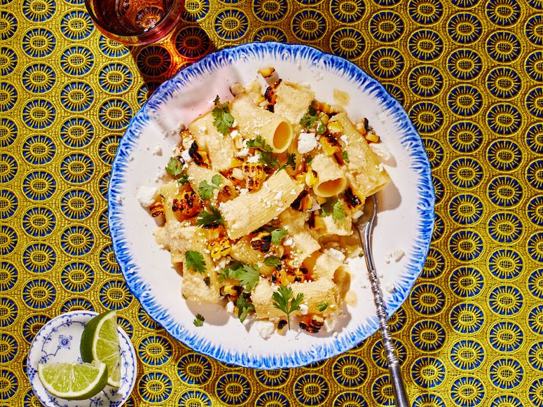 Bowl of corn elote pasta on yellow background.