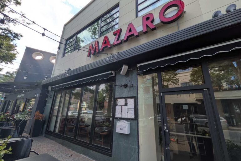 Exterior view of a modern storefront with a red MAZARO sign, string lights, and large glass windows.
