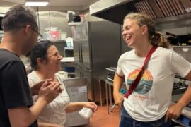Polly stands in the kitchen laughing with two other chefs
