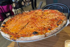 A cheese pizza on a tray on a restaurant table