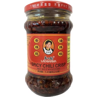 Jar of Spicy Chili Crisp with a red label and a portrait on the front.