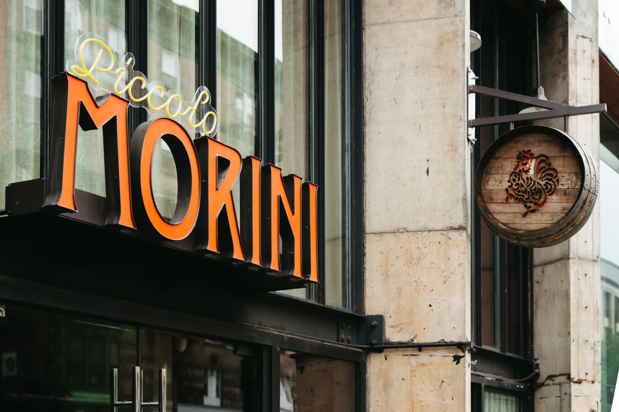 Restaurant exterior with orange 'Piccolo Morini' sign and round wooden rooster sign.