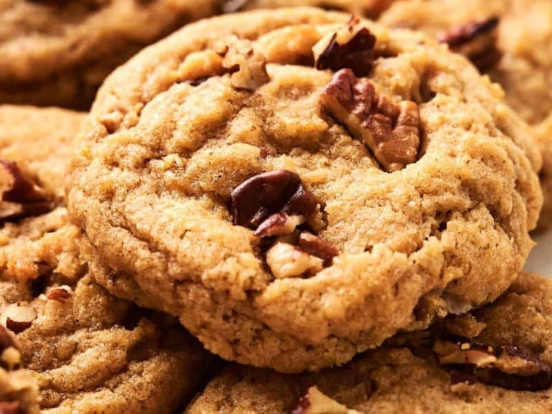 Close-up of freshly baked cookies with nuts on top, arranged closely together.